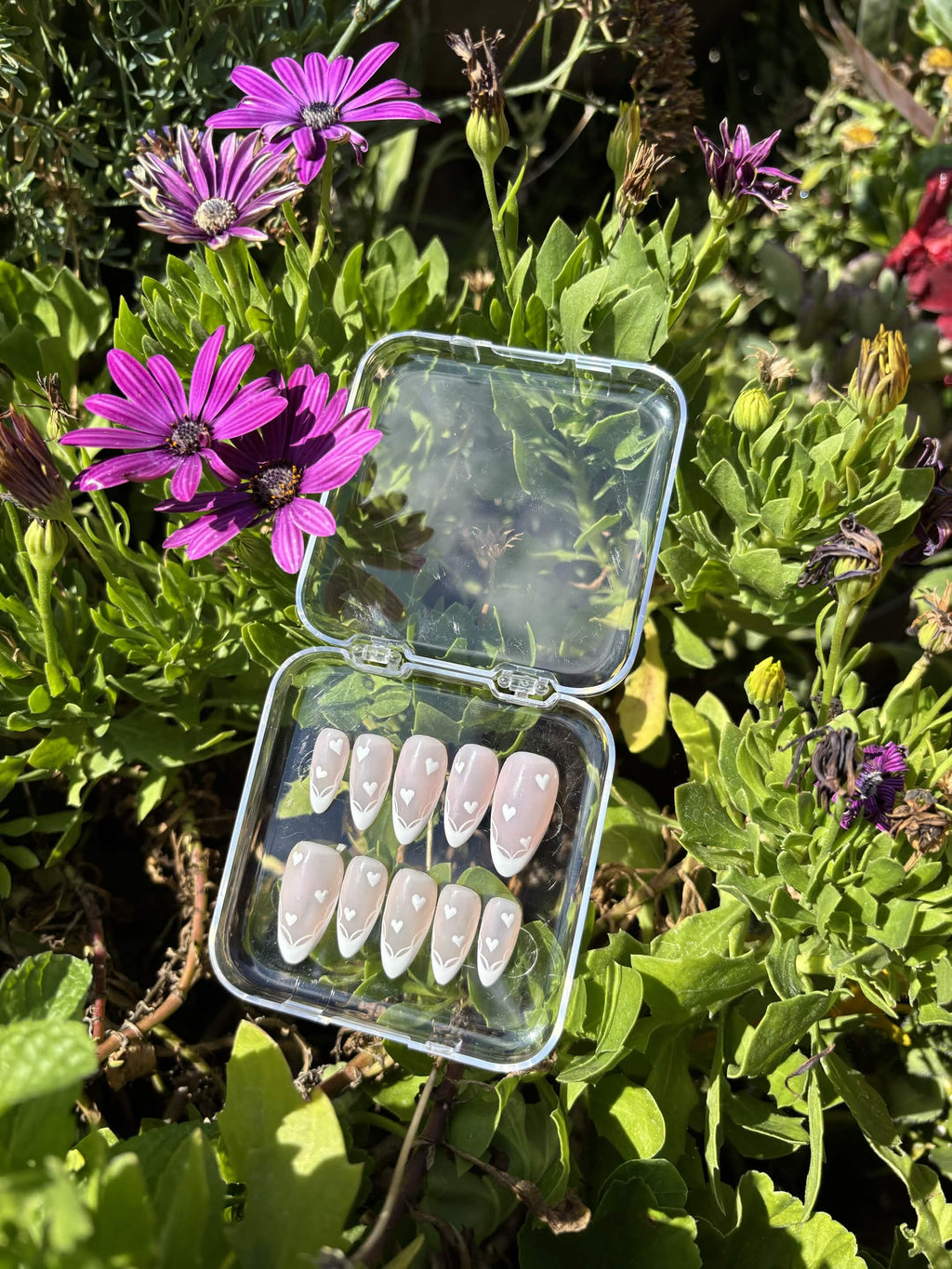 Close view of the Blushing Hearts set — tiny white hearts and delicate hand-painted line-work above each French tip