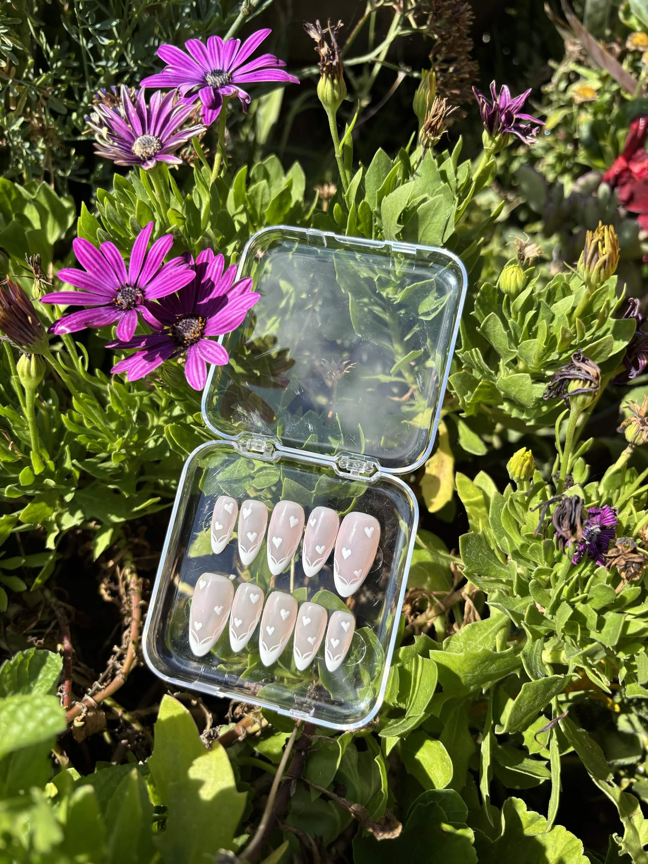 Close view of the Blushing Hearts set — tiny white hearts and delicate hand-painted line-work above each French tip